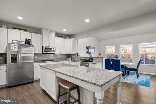 kitchen with a kitchen bar, white cabinets, a center island, and stainless steel appliances