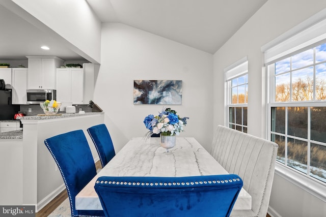 dining space featuring vaulted ceiling and hardwood / wood-style floors