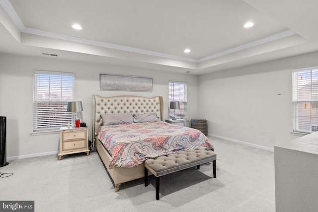 bedroom with ornamental molding, light colored carpet, and a tray ceiling