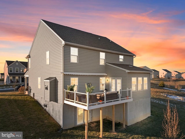 back house at dusk with a lawn