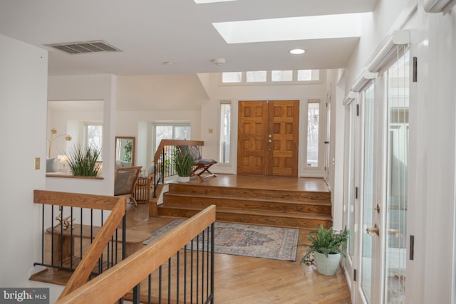 foyer entrance with recessed lighting, a skylight, wood finished floors, visible vents, and stairs