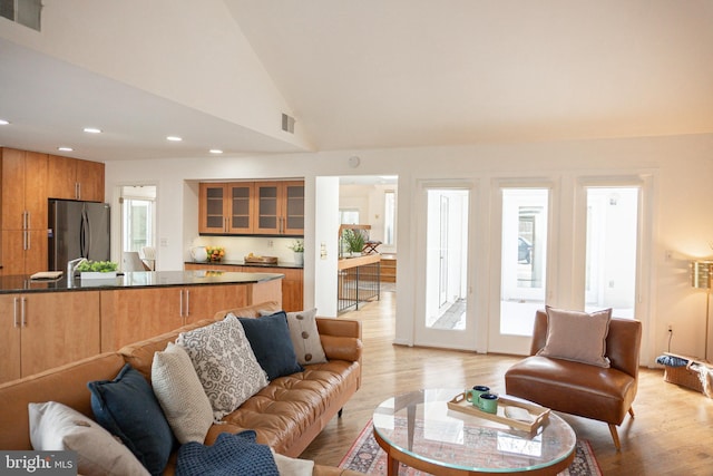 living area with lofted ceiling, light wood-type flooring, visible vents, and recessed lighting