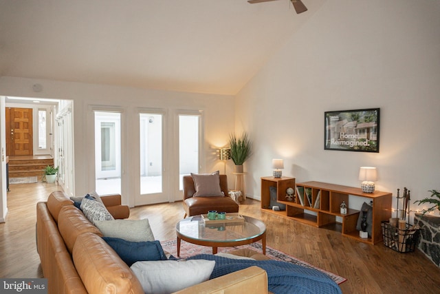 living area with high vaulted ceiling, ceiling fan, and wood finished floors