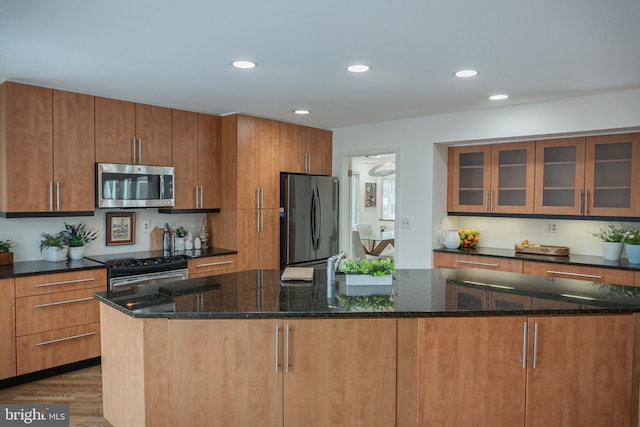 kitchen with dark stone counters, appliances with stainless steel finishes, wood finished floors, and recessed lighting