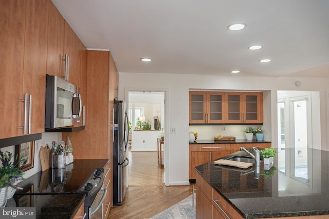 kitchen featuring stainless steel appliances, brown cabinetry, a sink, and light wood-style floors