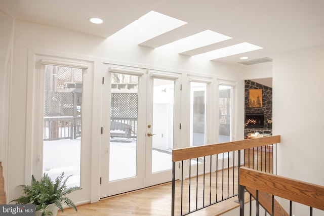 doorway to outside featuring recessed lighting, a fireplace, wood finished floors, visible vents, and french doors