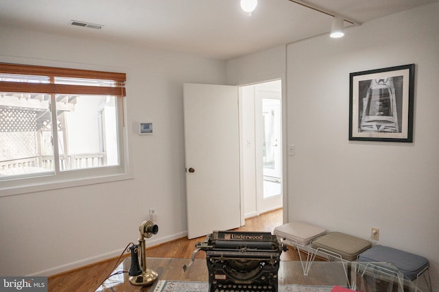 interior space with baseboards, track lighting, visible vents, and wood finished floors