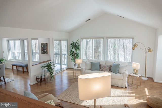 living area with lofted ceiling, baseboards, visible vents, and wood finished floors