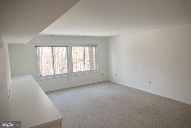 empty room featuring light colored carpet and baseboards