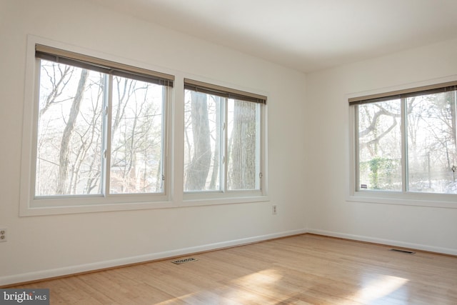 spare room featuring visible vents, baseboards, and wood finished floors