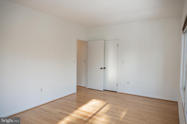 unfurnished bedroom featuring baseboards, a closet, and light wood-style floors