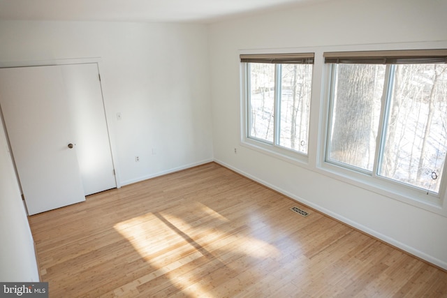 unfurnished room featuring wood finished floors, visible vents, and baseboards