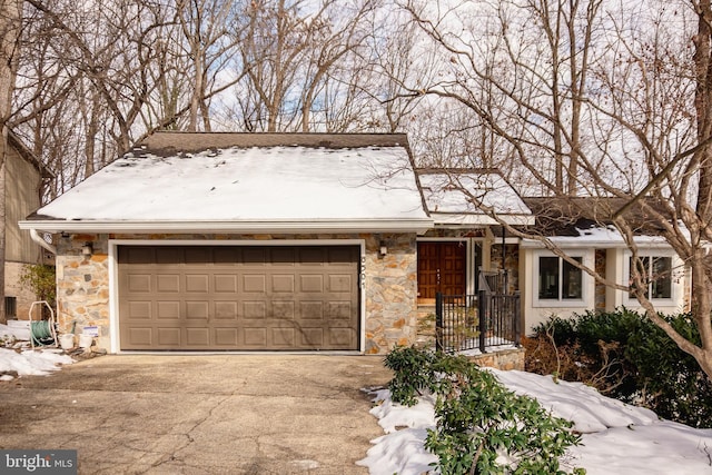 single story home featuring stone siding, driveway, and an attached garage