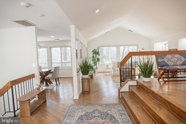 interior space with visible vents, vaulted ceiling, wood finished floors, baseboards, and stairs