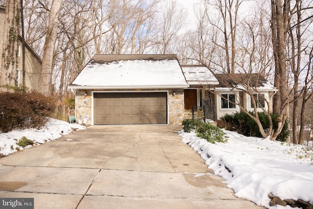 ranch-style home with stone siding, driveway, and an attached garage