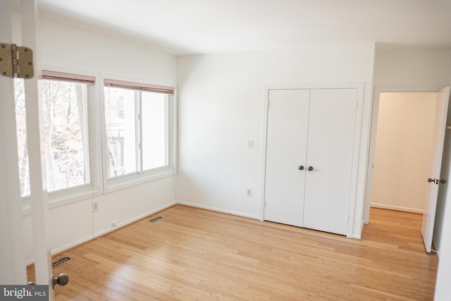 unfurnished bedroom with light wood-style floors, a closet, visible vents, and baseboards