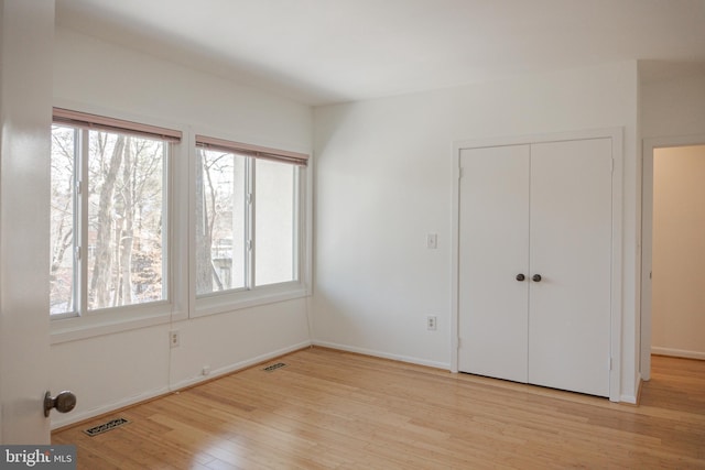 unfurnished bedroom with light wood finished floors, multiple windows, and visible vents