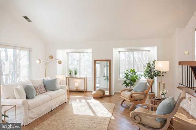 living room with lofted ceiling, light wood-style flooring, plenty of natural light, and visible vents