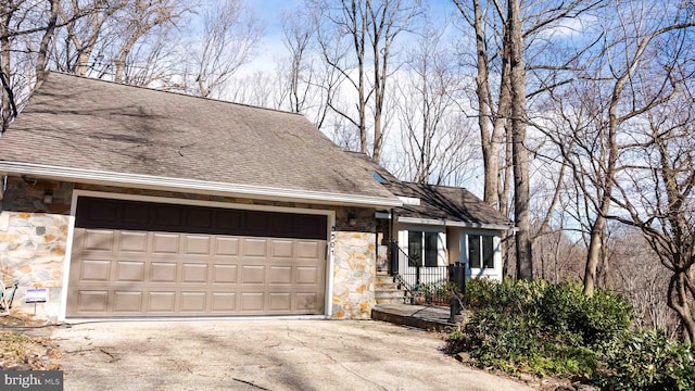 view of front of property with stone siding, roof with shingles, driveway, and an attached garage