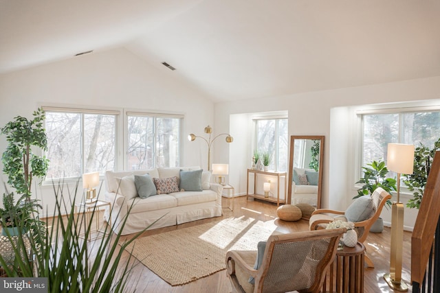 living room with lofted ceiling, light wood-style flooring, plenty of natural light, and visible vents