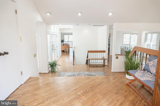 hall with a wealth of natural light, visible vents, wood finished floors, and recessed lighting