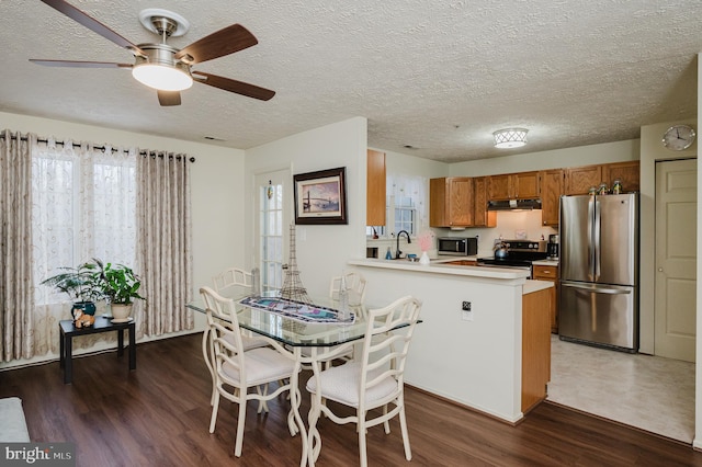 dining room with ceiling fan, dark wood-type flooring, and a textured ceiling