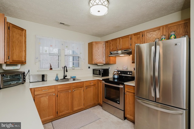 kitchen featuring sink, a textured ceiling, and stainless steel appliances