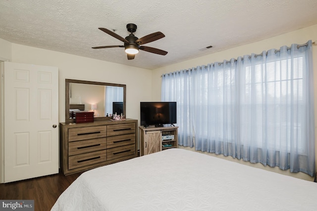 bedroom featuring ceiling fan, dark wood-type flooring, and a textured ceiling