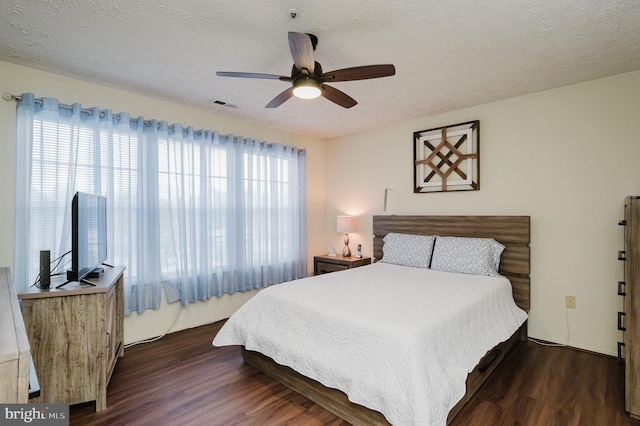 bedroom featuring dark wood-type flooring, ceiling fan, a textured ceiling, and multiple windows