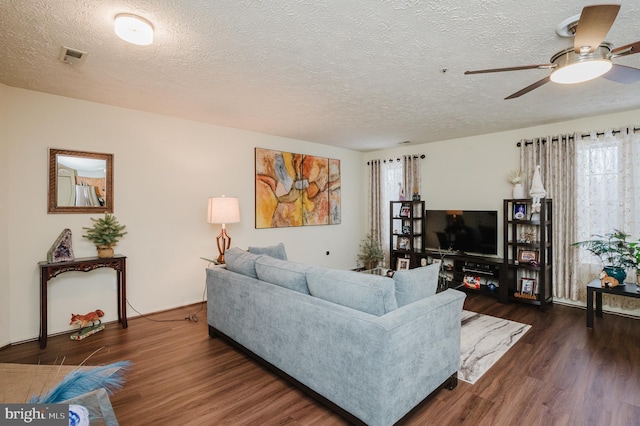 living room featuring ceiling fan, dark hardwood / wood-style floors, a wealth of natural light, and a textured ceiling