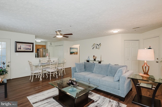 living room with ceiling fan, dark hardwood / wood-style flooring, and a textured ceiling