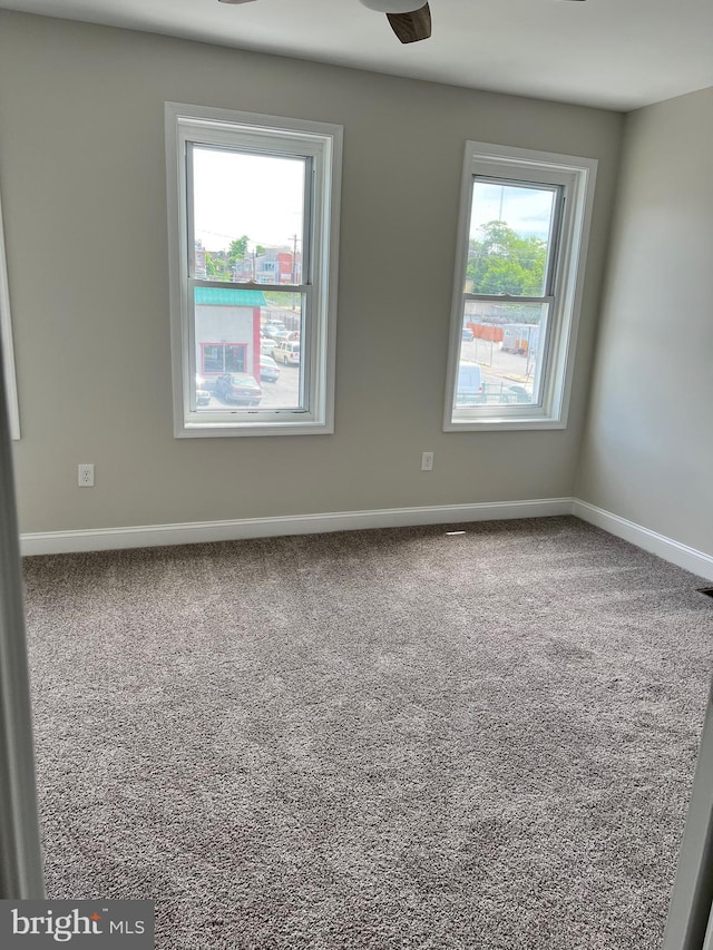 carpeted spare room featuring ceiling fan