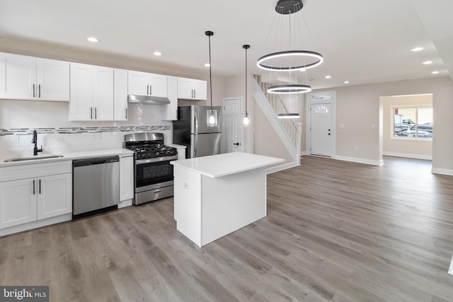 kitchen featuring stainless steel appliances, hanging light fixtures, decorative backsplash, sink, and white cabinetry