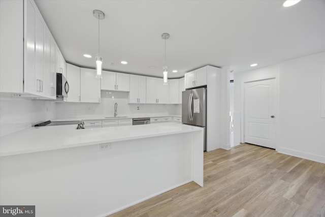 kitchen featuring sink, white cabinets, kitchen peninsula, hanging light fixtures, and appliances with stainless steel finishes