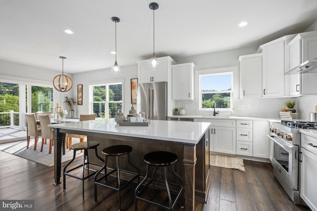 kitchen with decorative light fixtures, white cabinets, high end appliances, and a center island