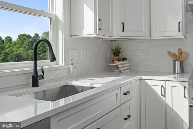 kitchen featuring white cabinets, decorative backsplash, plenty of natural light, and sink