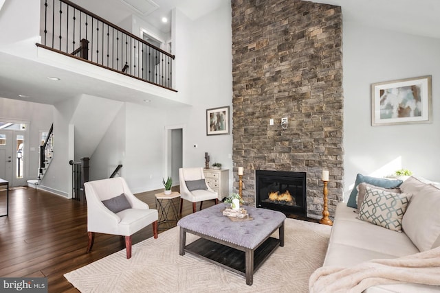 living room with high vaulted ceiling, wood-type flooring, and a stone fireplace