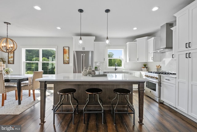 kitchen with pendant lighting, premium appliances, a center island, wall chimney exhaust hood, and backsplash