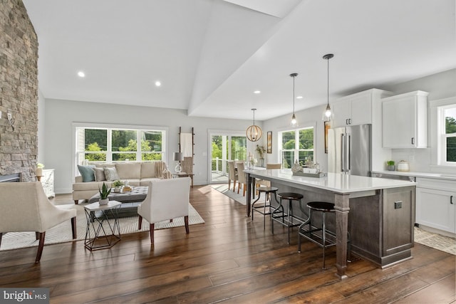 kitchen with high quality fridge, white cabinets, a kitchen island, hanging light fixtures, and a breakfast bar area