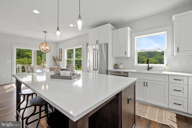 kitchen featuring white cabinets, a center island, stainless steel appliances, sink, and backsplash