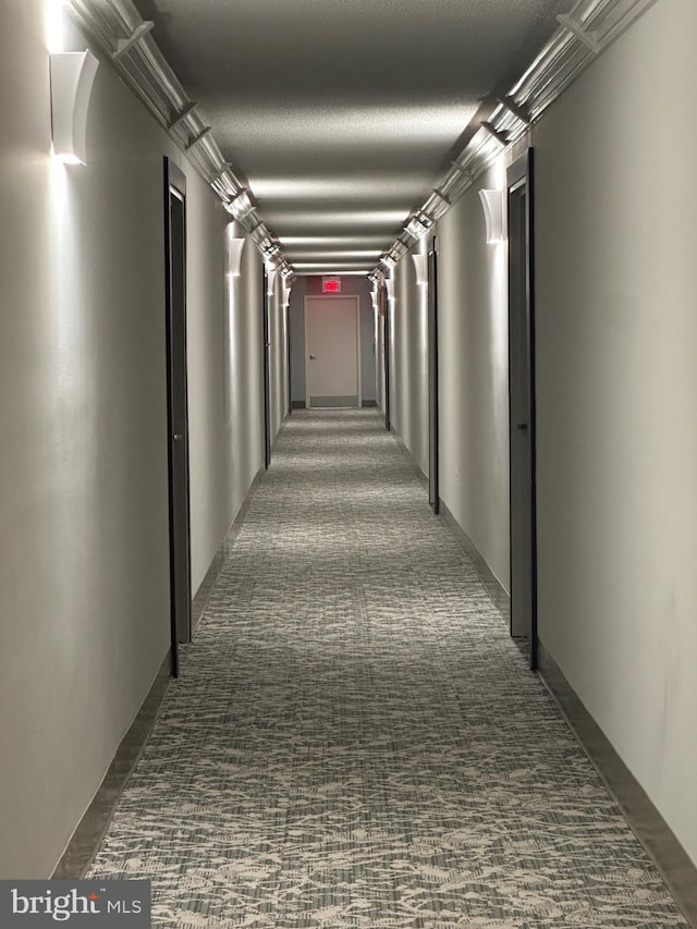 hallway featuring a textured ceiling and dark colored carpet