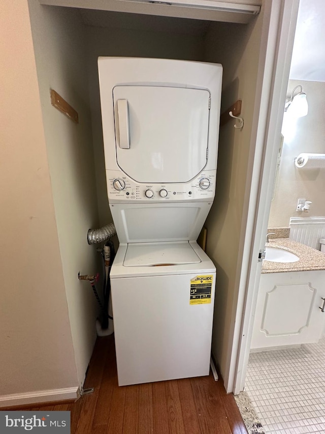 laundry room featuring hardwood / wood-style floors and stacked washer and clothes dryer