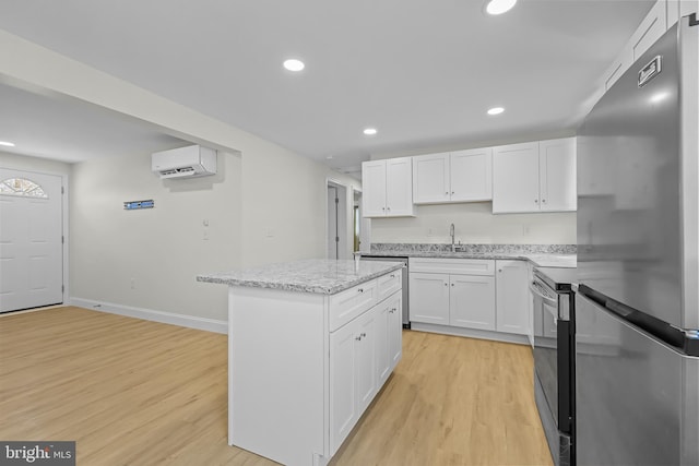 kitchen with stainless steel appliances, white cabinetry, sink, and a center island