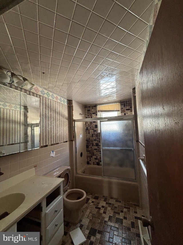 full bathroom featuring tile walls, toilet, vanity, and enclosed tub / shower combo