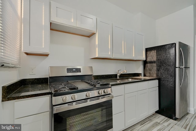 kitchen with stainless steel appliances, dark stone countertops, white cabinets, and sink