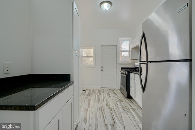 kitchen with stainless steel appliances, dark stone countertops, and white cabinets