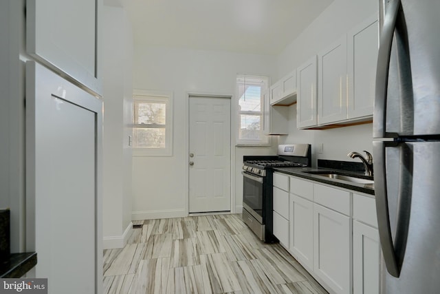 kitchen featuring stainless steel appliances, white cabinets, sink, and a healthy amount of sunlight