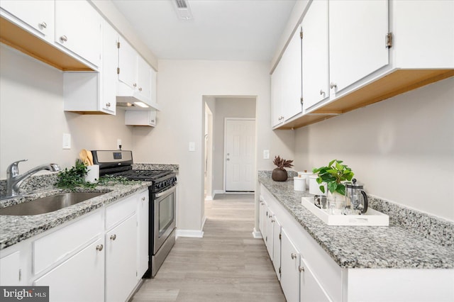 kitchen with sink, stainless steel gas stove, white cabinets, and light hardwood / wood-style flooring