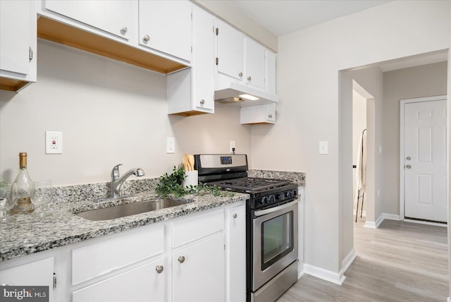 kitchen featuring sink, white cabinets, light stone counters, light hardwood / wood-style floors, and gas stove