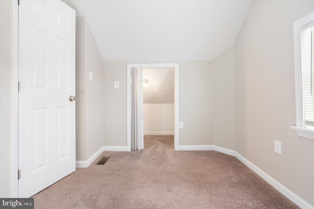 unfurnished bedroom with carpet flooring and vaulted ceiling